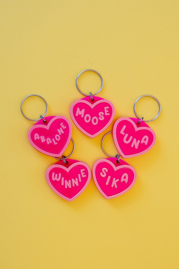 Heart-shaped keychains with personalized names on a yellow background